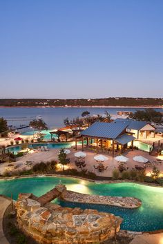 an aerial view of a resort at night with lights on the pool and water features