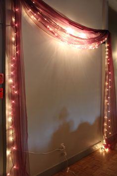 a room with some lights on the wall and a red curtain hanging from it's side