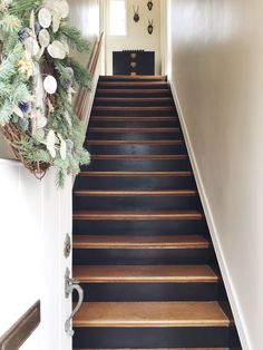 a set of stairs leading up to a door with wreaths on the top and bottom