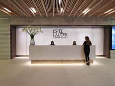 a woman standing in front of a white reception desk with flowers on it and the name estte ladder companies