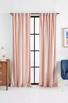 a living room with pink curtains and a blue chair