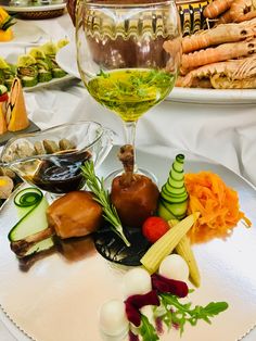 a glass of wine sitting on top of a white plate covered in vegetables and veggies