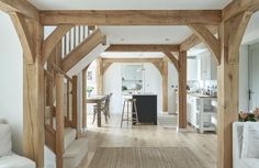 an open concept kitchen and dining area with wooden beams on the ceiling, hardwood flooring, and white walls