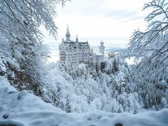 a snow covered castle in the middle of trees with lots of snow on it's sides