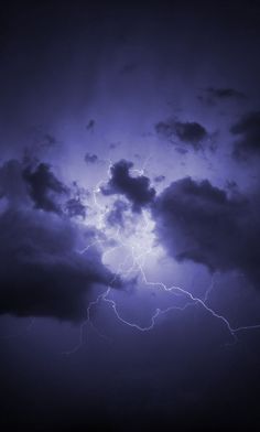 the sky is filled with clouds and lightnings as it breaks into dark blue hues