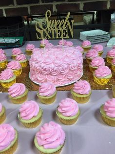 pink cupcakes are arranged on a table in front of a sweet sixteen sign