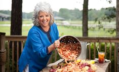 a woman holding a pot full of food on top of a table