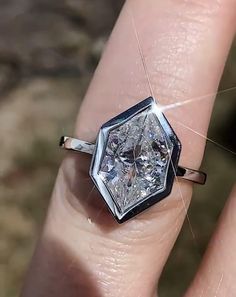 a woman's hand with a diamond ring on top of her finger, showing the center stone