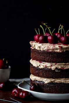 a chocolate cake topped with cherries on top of a white plate