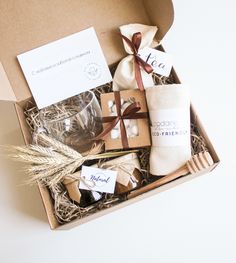 a box filled with different types of food and wine glasses, wrapped in brown paper