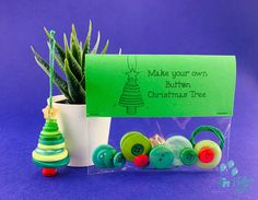 a small potted plant sitting on top of a table next to a sign that says make your own button christmas tree