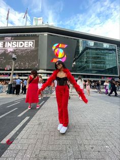 a woman dressed in red dancing on the street