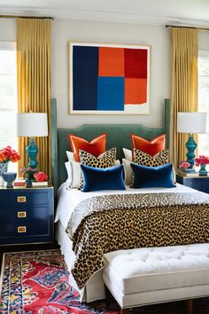 a bedroom with leopard print bedding and colorful pillows on the headboard, along with an animal print rug