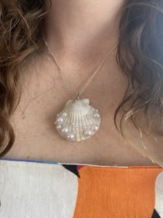 a close up of a person wearing a necklace with a shell on the back of her neck