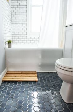 a white toilet sitting next to a bath tub in a bathroom on top of a blue tiled floor