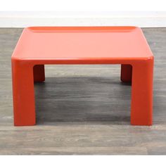 an orange plastic table sitting on top of a hard wood floor