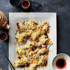 an overhead view of food on a plate with chopsticks, sauce and utensils