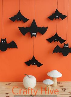 a group of bats hanging from strings next to mushrooms and an apple on a table