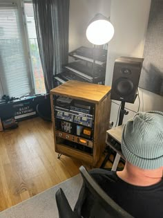 a man sitting in front of a radio next to a desk with sound equipment on it