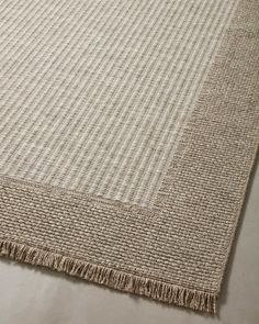 a beige rug with fringes on top of it