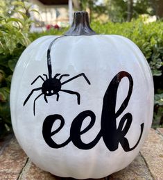 a white pumpkin with the word eef painted on it and a spider sitting on top