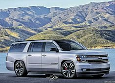 the new chevrolet suburban suv is parked in front of a mountain lake with mountains in the background