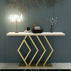 a modern console table with gold and white lines on the top, in front of a blue wall