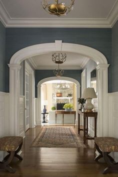 an archway leading into a living room with two benches and a lamp on the wall