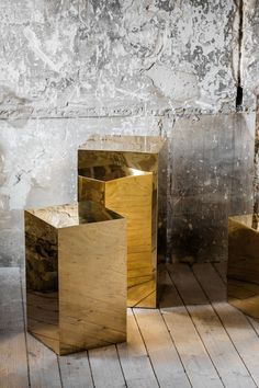 three wooden cubes sitting next to each other on top of a wooden floor in front of a stone wall