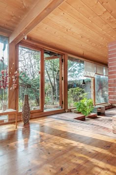 a living room with wood floors and large windows overlooking the trees in the distance is shown