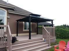 an outdoor patio with two chairs and a gazebo on the side of a house