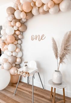 a balloon arch is decorated with white and pink balloons, one word on the wall