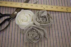 two white roses sitting next to a pair of scissors