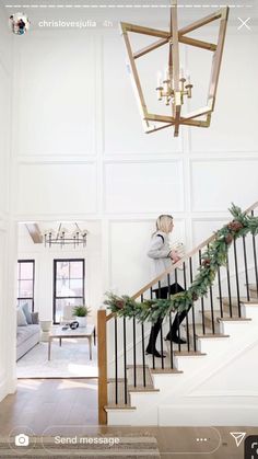 a person walking down the stairs in a house with christmas decorations on it's handrails