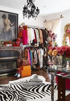 a zebra rug is in front of a closet full of clothes and accessories, with a chandelier hanging from the ceiling