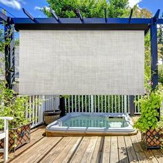 a hot tub sitting on top of a wooden deck next to potted plants and trees