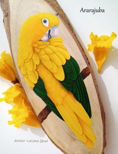 a yellow and green bird sitting on top of a piece of wood next to flowers