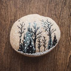 a painted rock with trees and snow on it