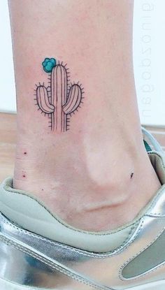 a small cactus tattoo on the side of a woman's foot with a blue flower