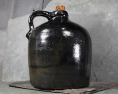 a black jug sitting on top of a stone slab