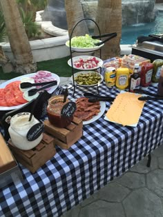 a table with food and drinks on it next to a swimming pool in the background