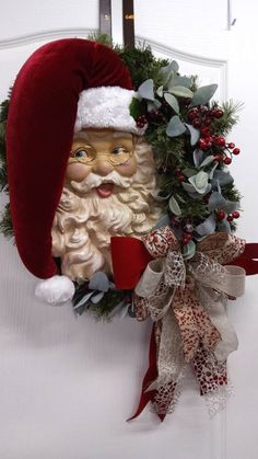 a christmas wreath with santa claus on it hanging from the side of a white door