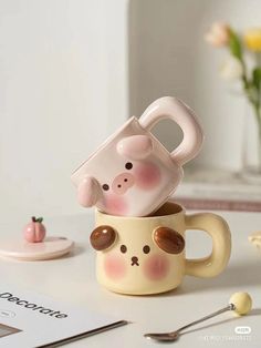 two mugs that have been placed on top of each other, one is shaped like a pig