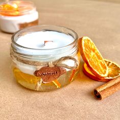 an orange slice next to a glass jar filled with liquid and cinnamon sticks on a table