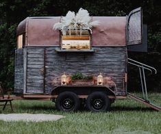 an old trailer converted into a tiny house with lights on the windows and flowers in the window