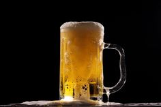 a glass of beer sitting on top of a table