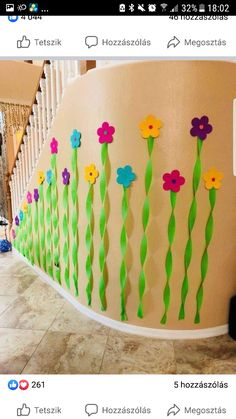 flowers are painted on the side of a wall with green grass and straws attached to it