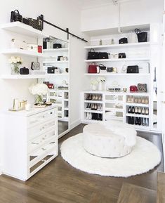 a room with white shelves and shelving filled with shoes, handbags and purses