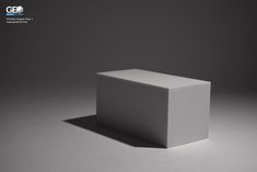 a white cube sitting on top of a gray floor in the middle of an empty room