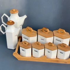 a wooden tray with teapots and cups on it next to a white pitcher